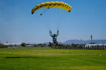 Paracaidista aterrizando sobre área verde especial para paracaidismo